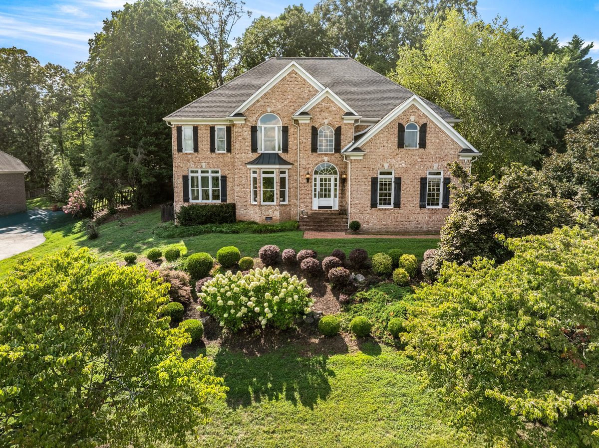 Low aerial view of a brick home with a landscaped front garden and mature trees, Knoxville TN