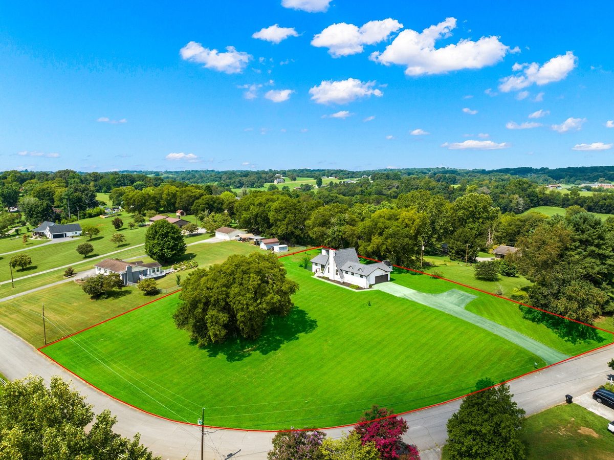 Aerial view of a white home on a large green lawn with the lot outlined in red, Maryville TN