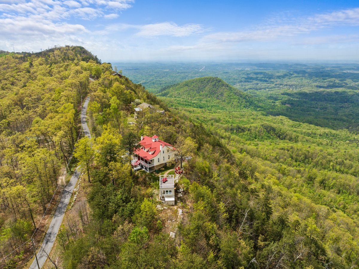Aerial view of a red roofed home on a forested ridge with valley views beyond, Pigeon Forge TN