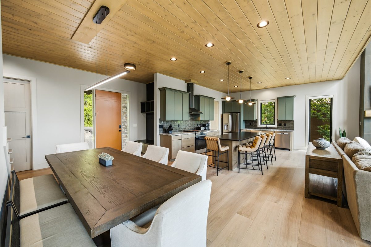 Dining table with upholstered chairs in an open kitchen and dining area under a wood plank ceiling, Sevierville TN