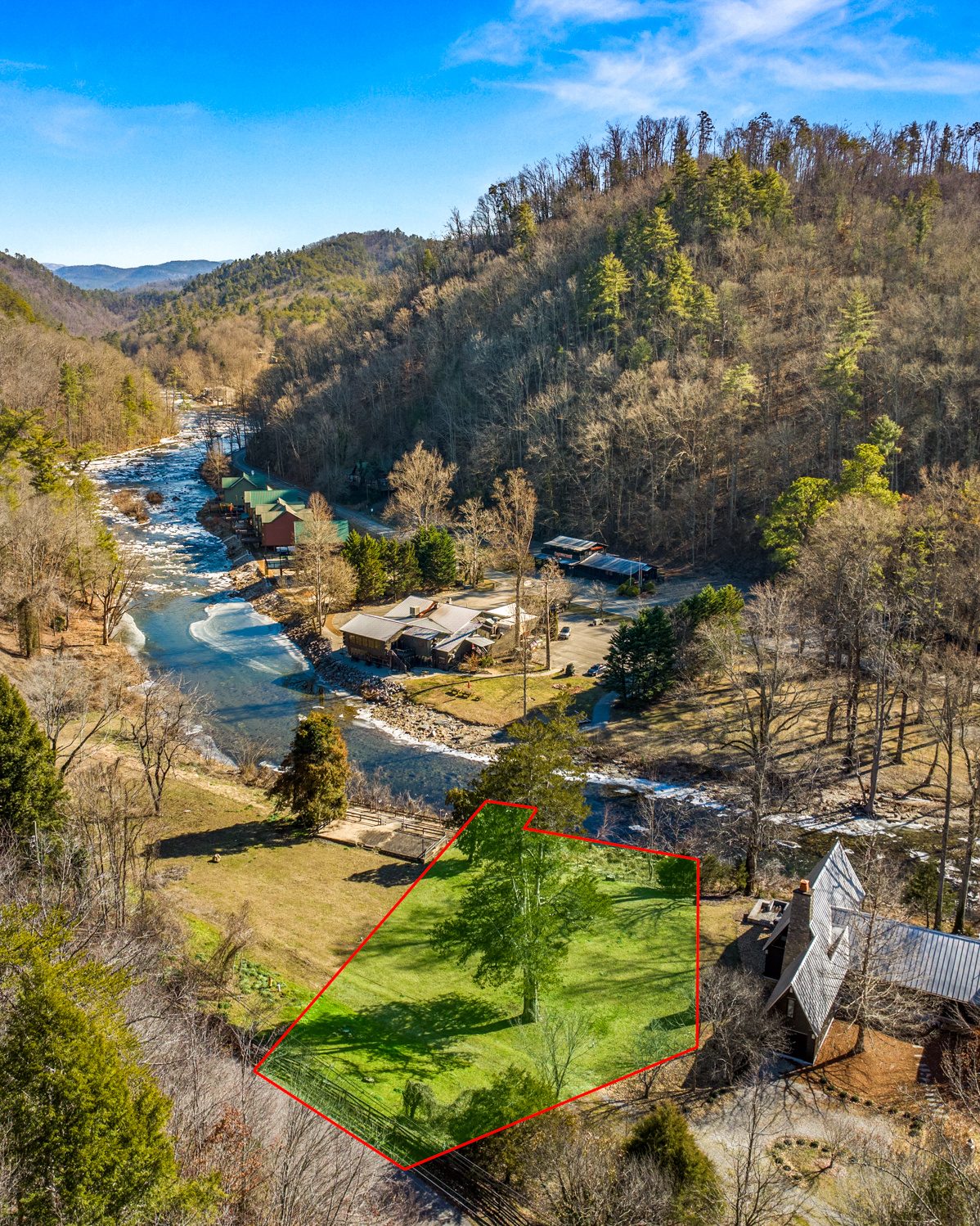 Aerial view of a grassy parcel outlined in red beside a rushing river in a wooded mountain valley, Tellico Plains TN