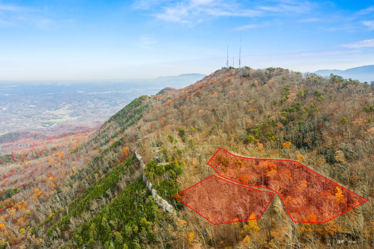Aerial view of wooded ridge parcels outlined in red in fall color, with towers on the summit and a valley below